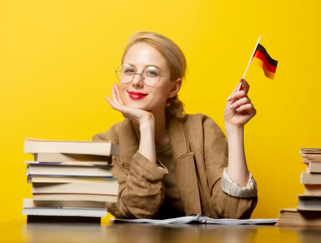 Style blonde woman sitting at table with books and flag of Germany on yellow background