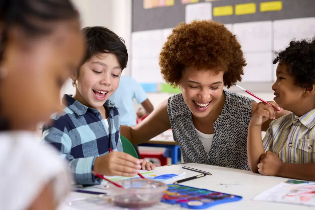 Female Teacher With Multi-Cultural Elementary School Pupils In Art Class At School