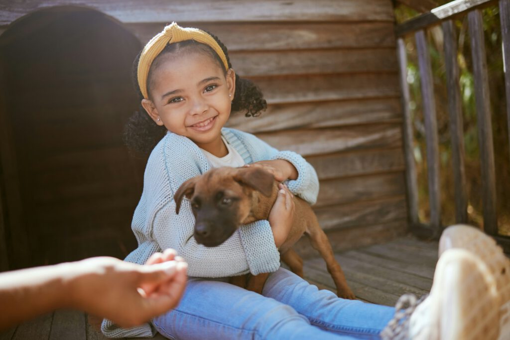 Portrait of girl child with puppy, happy outside and excited while hugging dog outside. Love, growt