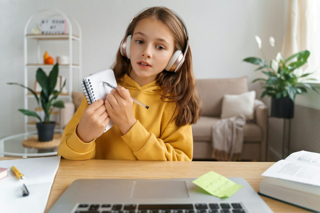 Portrait of girl showing notebook with exercise to her online teacher