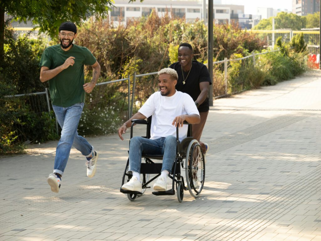 Three diverse male friends one of them in a wheelchair having fun in a city
