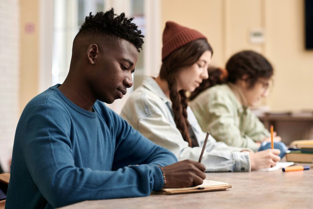 Young Black Man Writing in Notebook